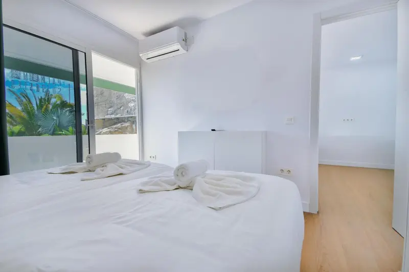 Une chambre lumineuse avec un grand lit recouvert de draps blancs et des serviettes.