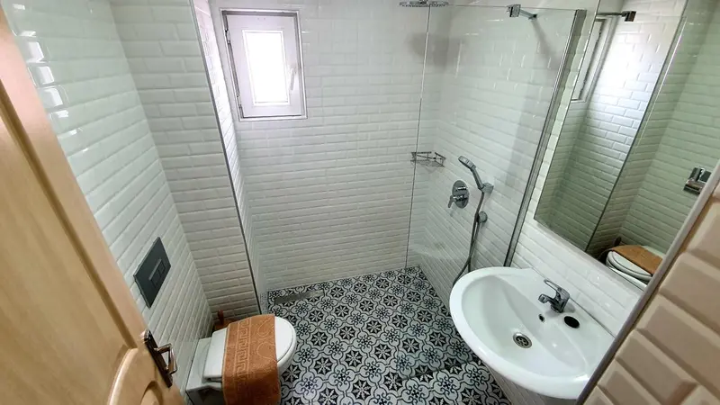 Une salle de bain claire avec douche à l'italienne et carrelage décoratif.