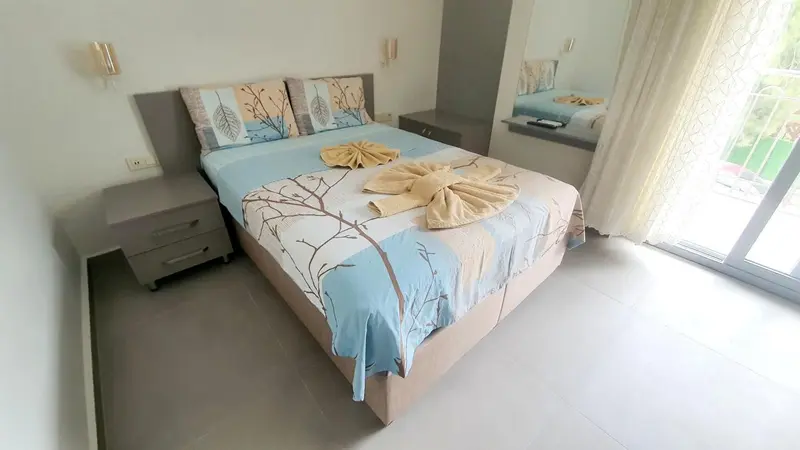 Une chambre lumineuse avec un lit double décoré de serviettes.