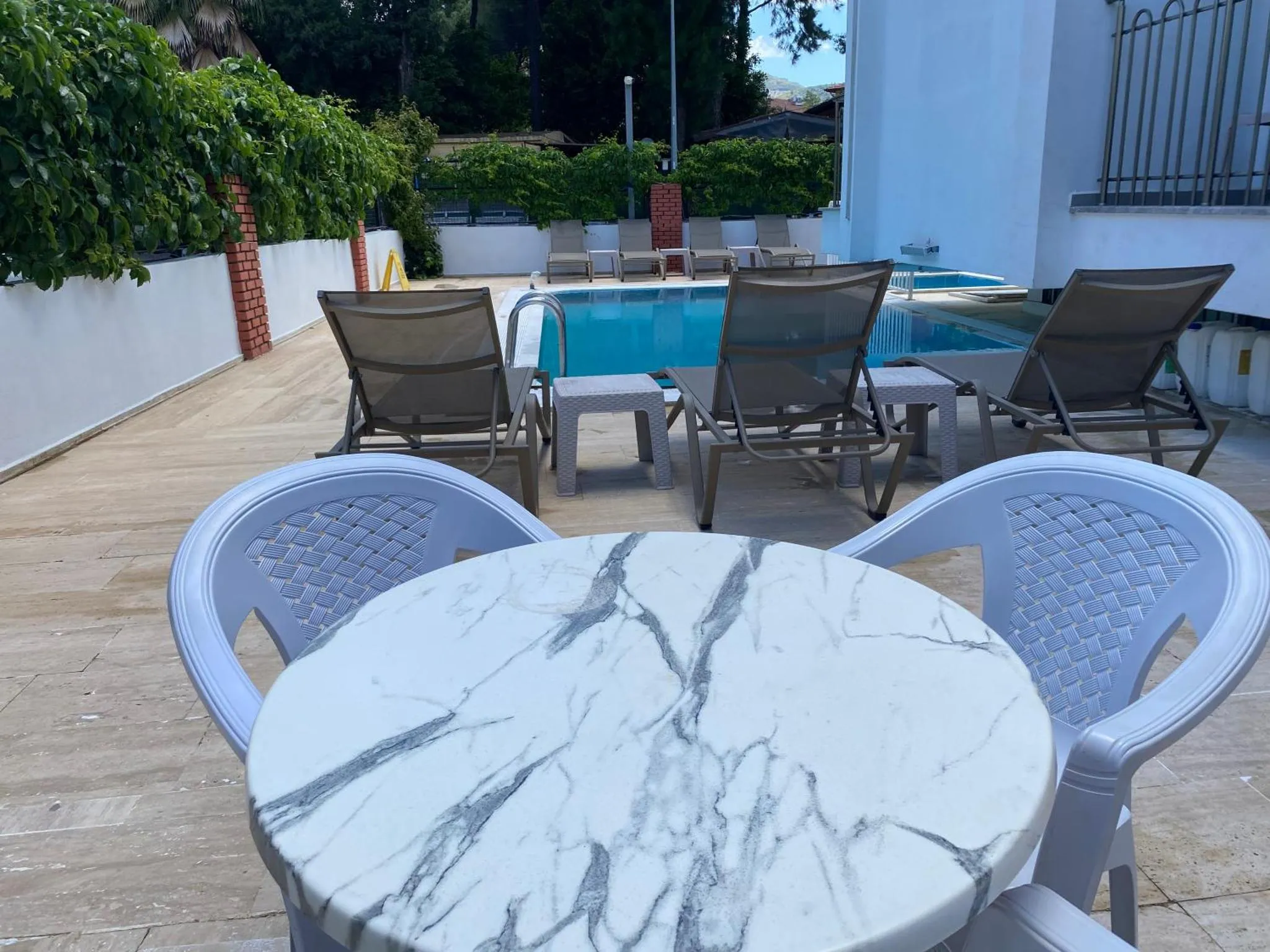 Terrasse avec mobilier de jardin et piscine au fond.
