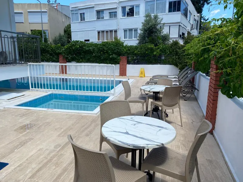 Terrasse avec tables et chaises près d'une piscine.