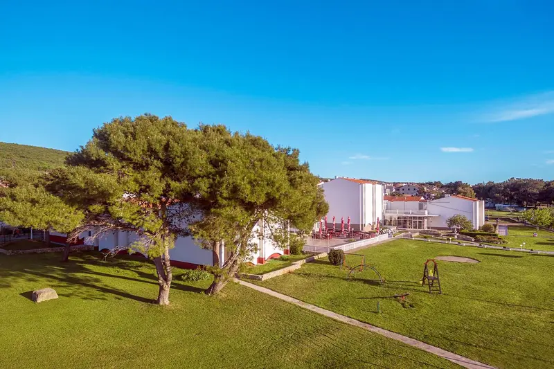 Bâtiment blanc avec des parasols sur une pelouse verte.