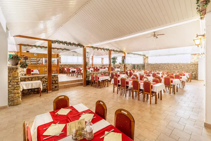 Une salle de restaurant lumineuse avec des tables dressées et un comptoir de service.