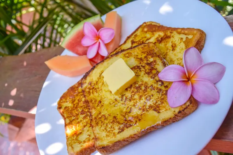 Assiette de pain perdu décorée de fruits et de fleurs.
