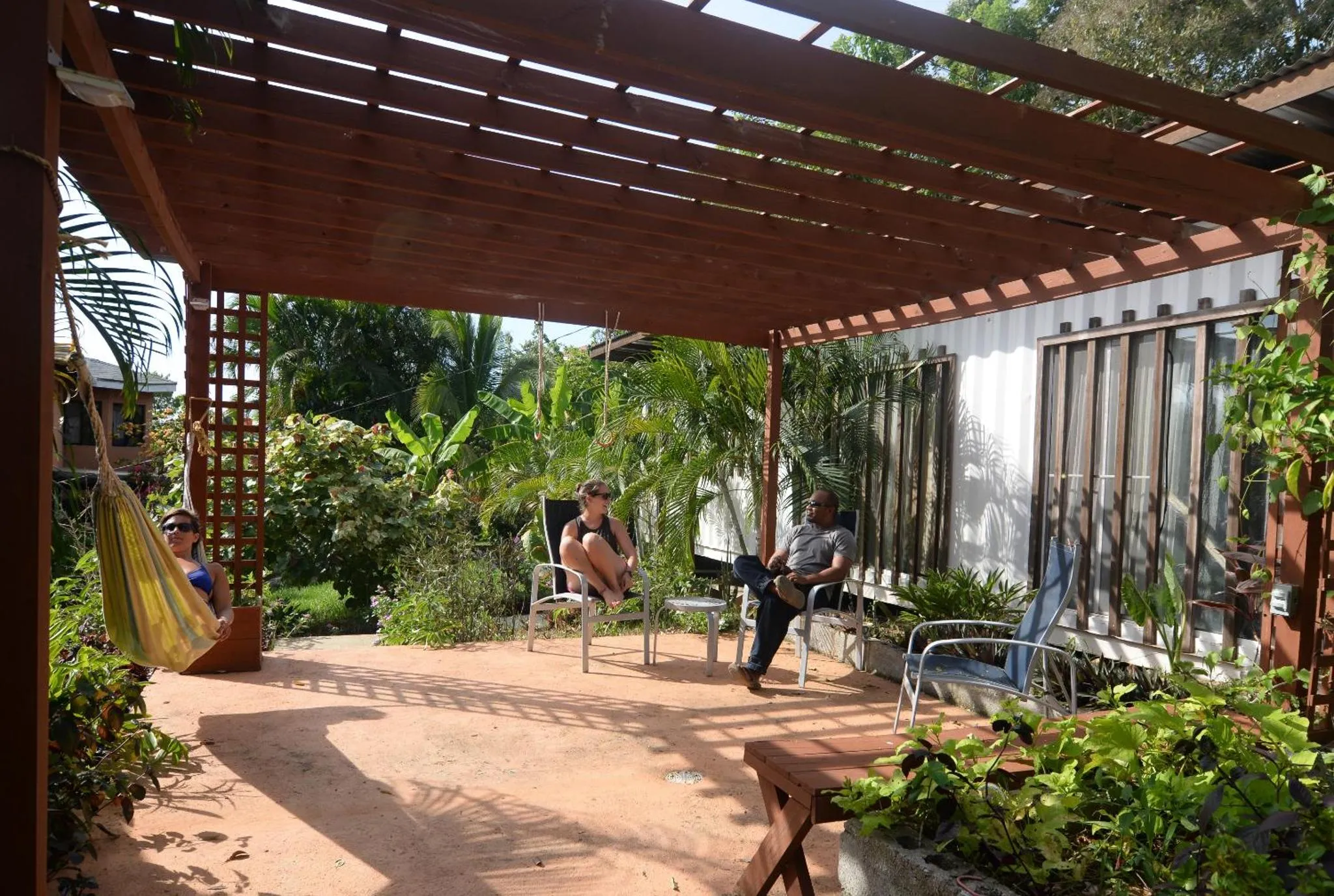Espace extérieur ombragé avec des personnes assises et un hamac.