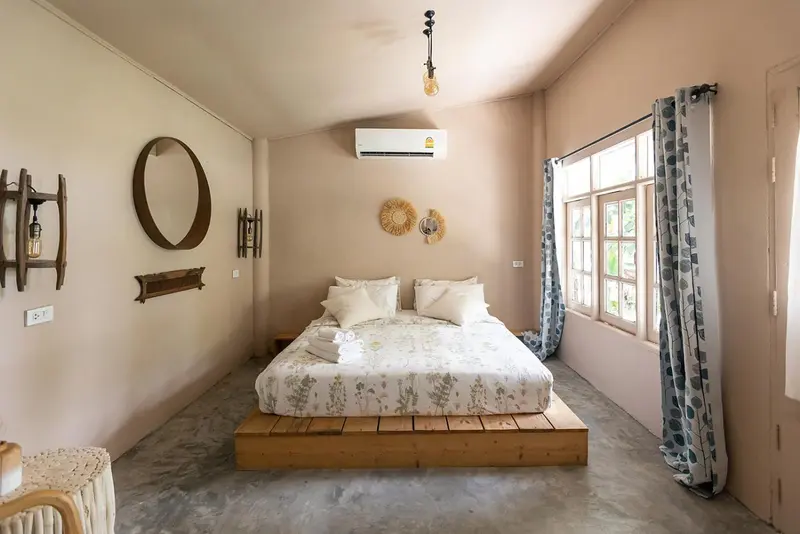 Une chambre lumineuse avec un grand lit recouvert de textiles clairs et des décorations murales.