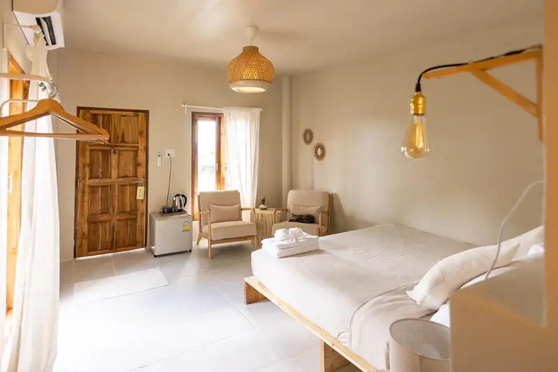 Une chambre lumineuse avec un lit fait et un fauteuil.