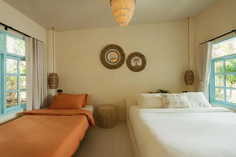 Chambre lumineuse avec deux lits et décoration murale.