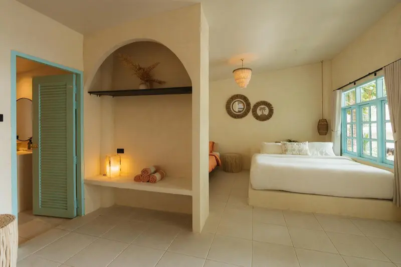 Une chambre lumineuse avec un lit blanc et des éléments de décoration murale.
