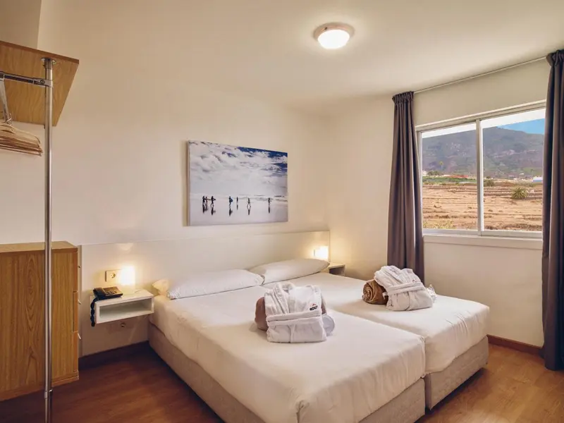 Une chambre lumineuse avec un grand lit et une vue sur un paysage montagneux.