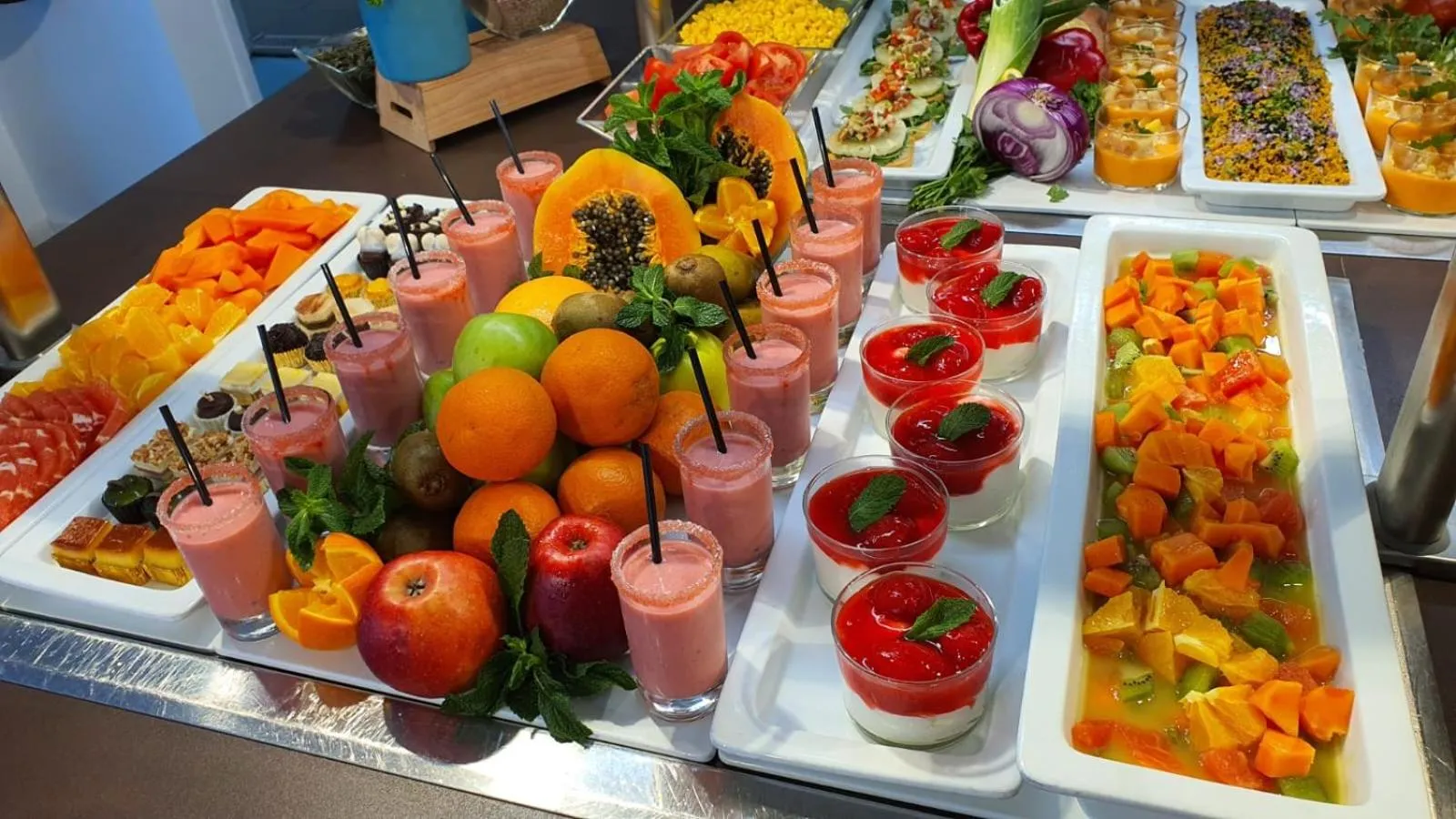Présentation colorée de fruits frais et de desserts en verrines sur un buffet.