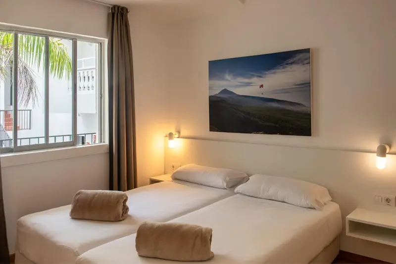 Une chambre lumineuse avec un grand lit et une vue sur un paysage tropical.
