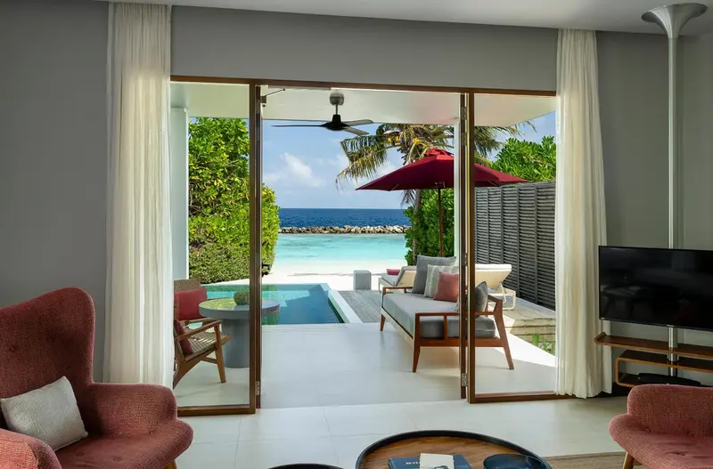 Une pièce lumineuse s'ouvre sur une terrasse avec piscine et vue sur la mer.