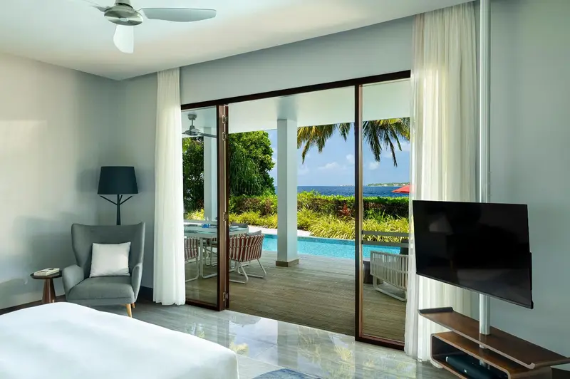 Une chambre lumineuse s'ouvre sur une terrasse avec piscine et vue sur la mer.