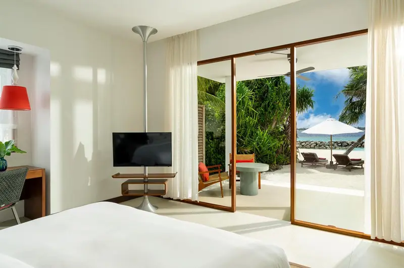 Une chambre lumineuse s'ouvre sur une terrasse donnant sur une plage.