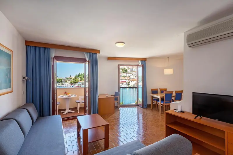 Une pièce lumineuse avec un canapé, une table basse et un coin repas donnant sur une vue dégagée.