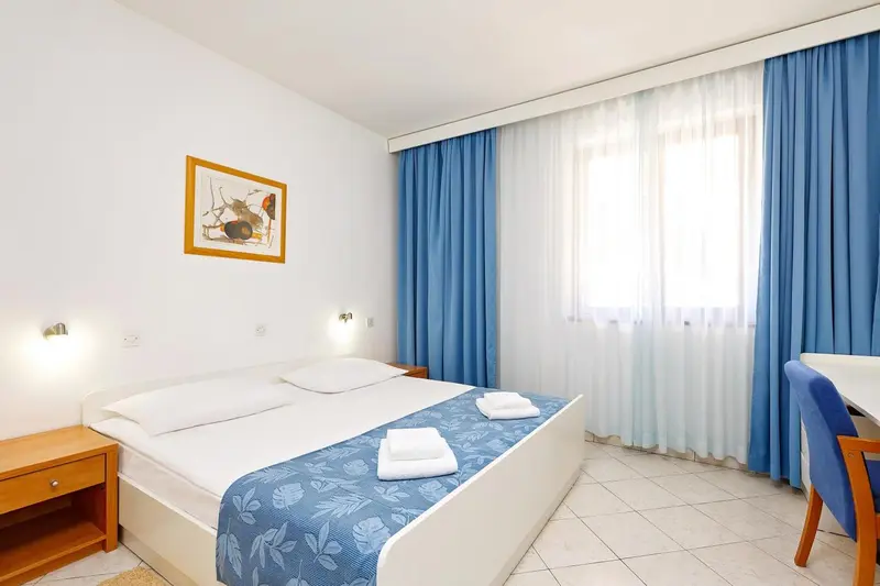 Une chambre lumineuse avec un grand lit et des rideaux bleus.