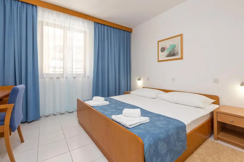 Chambre lumineuse avec un lit double et des rideaux bleus.