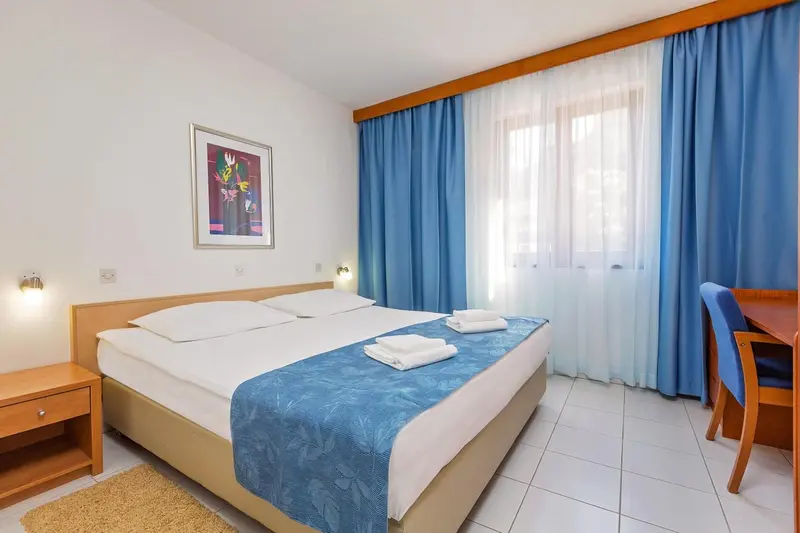 Chambre lumineuse avec un grand lit et un bureau.