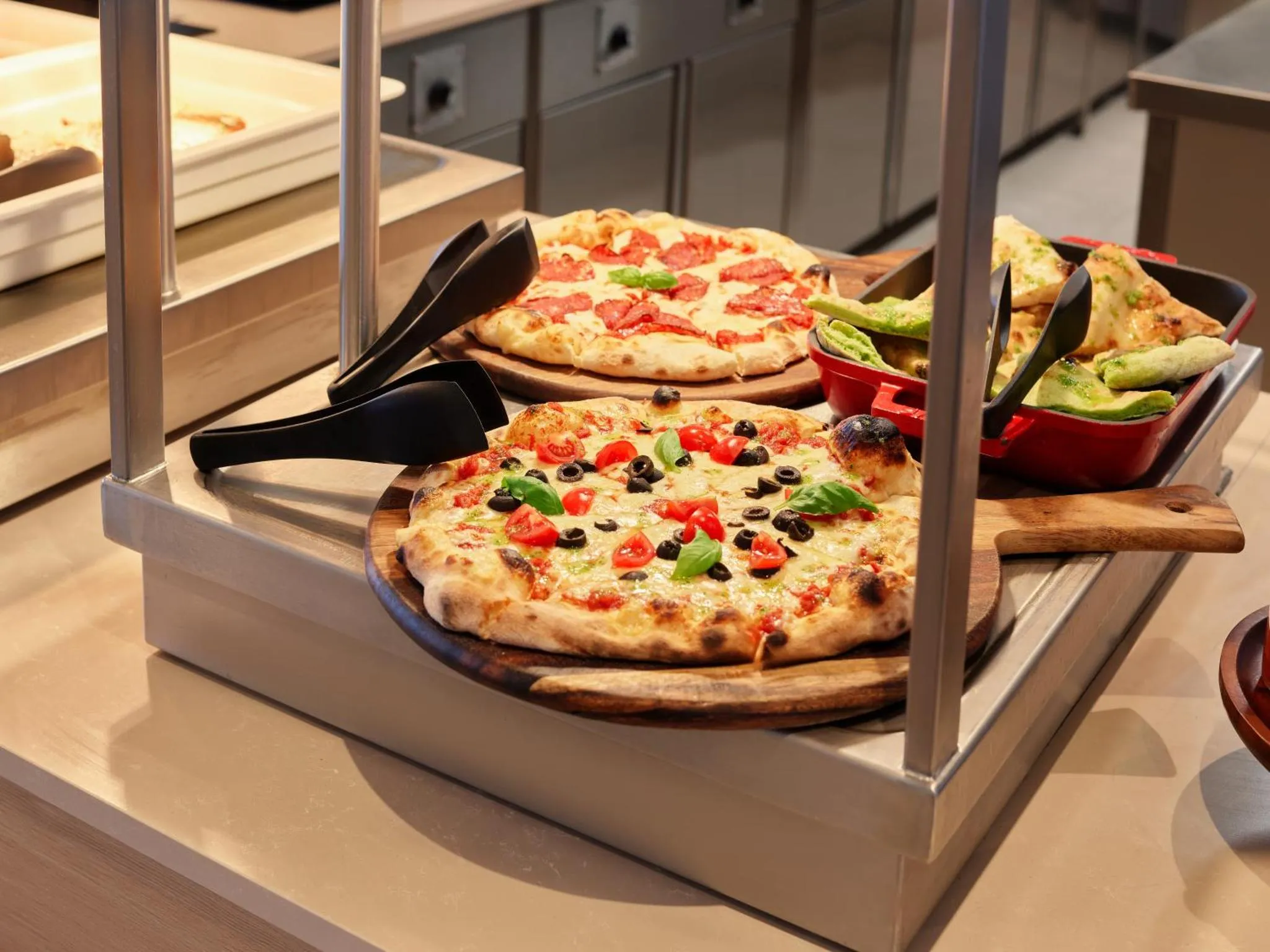 Présentation de pizzas et de tartes sur un buffet.