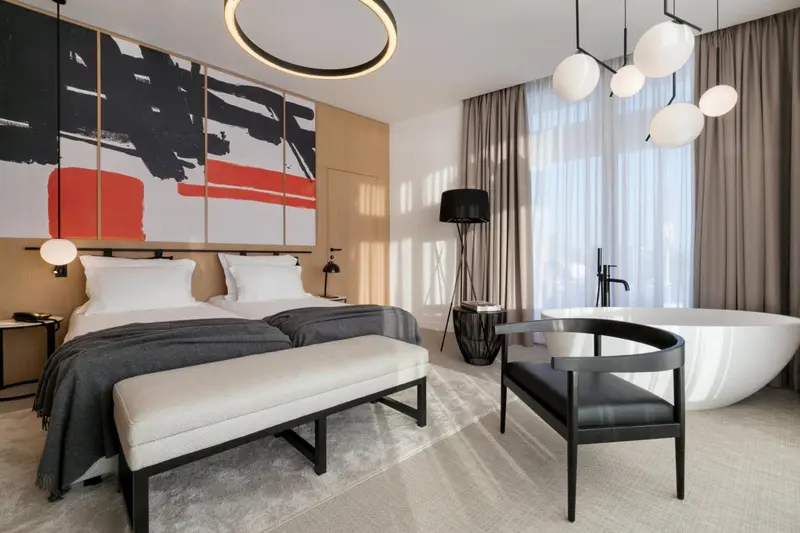 Une chambre moderne avec un grand lit et une baignoire sur pied.