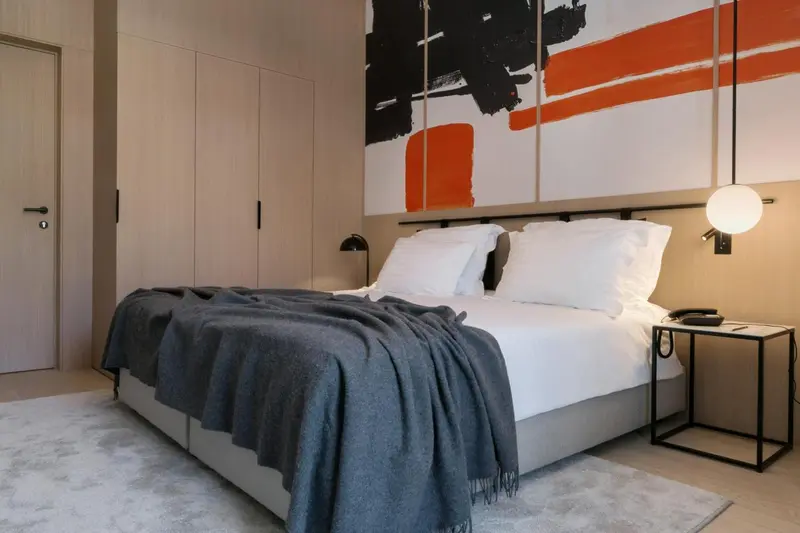 Une chambre moderne avec un grand lit et une décoration murale abstraite.