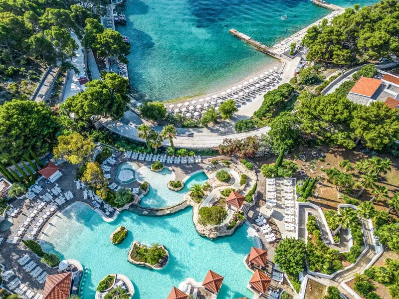 Vue aérienne d'un complexe hôtelier avec piscines et accès à la plage.