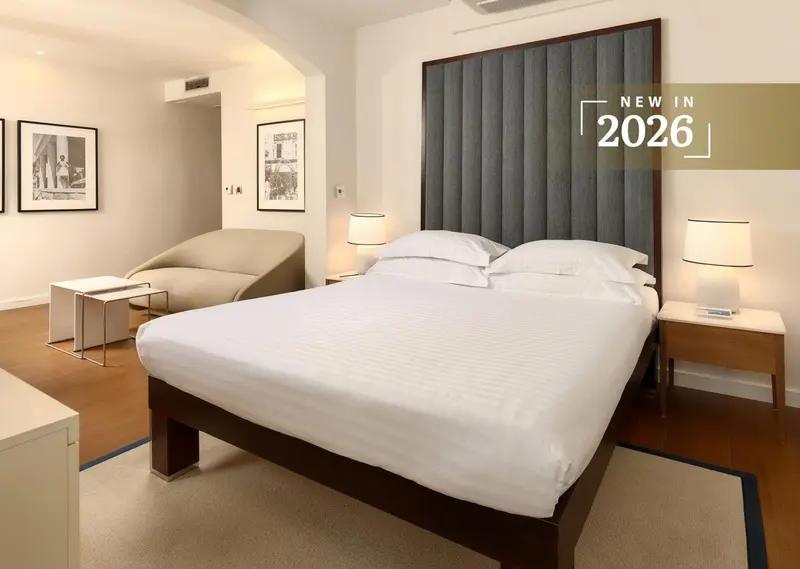 Une chambre lumineuse avec un grand lit et un fauteuil.