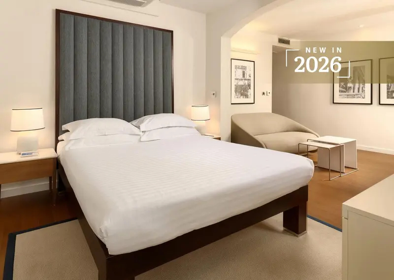 Une chambre lumineuse avec un grand lit et un fauteuil.