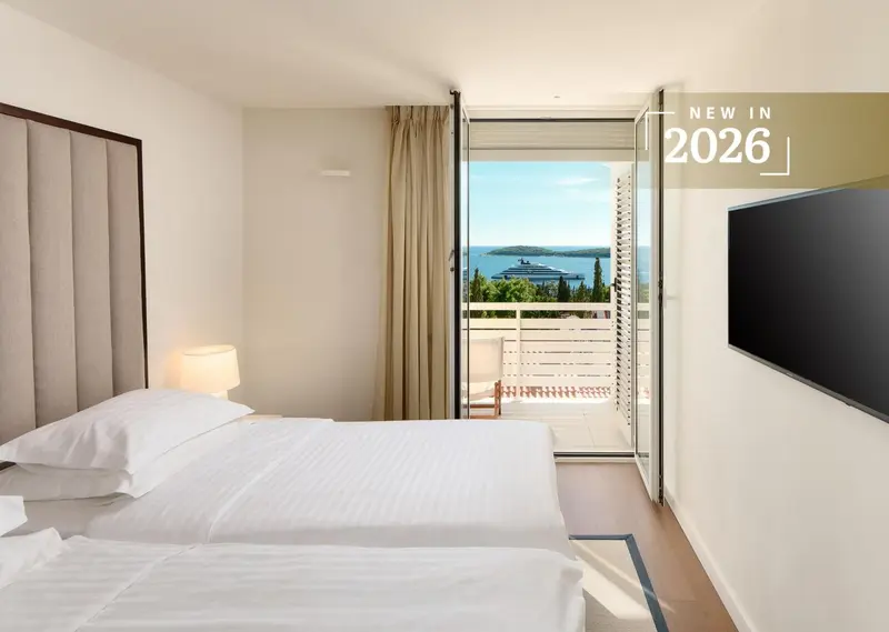 Chambre lumineuse avec un grand lit donnant sur une vue mer.