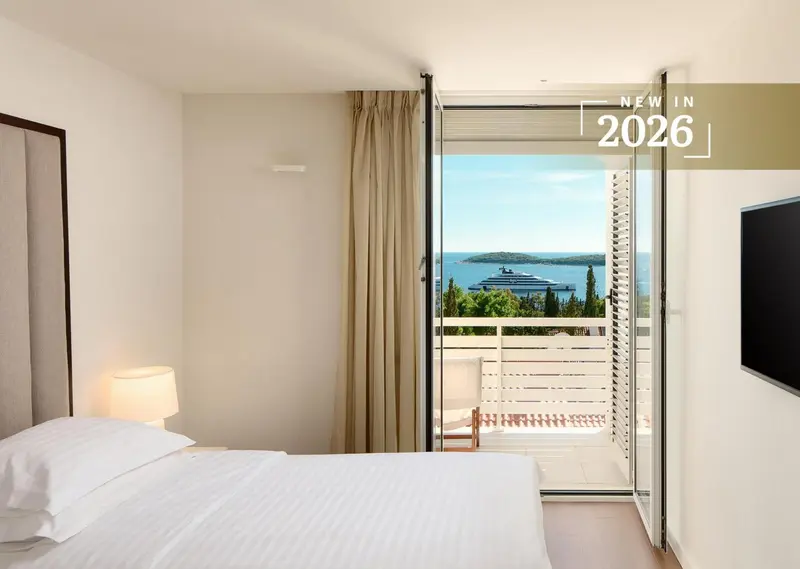 Une chambre lumineuse s'ouvre sur une vue mer par de grandes baies vitrées.