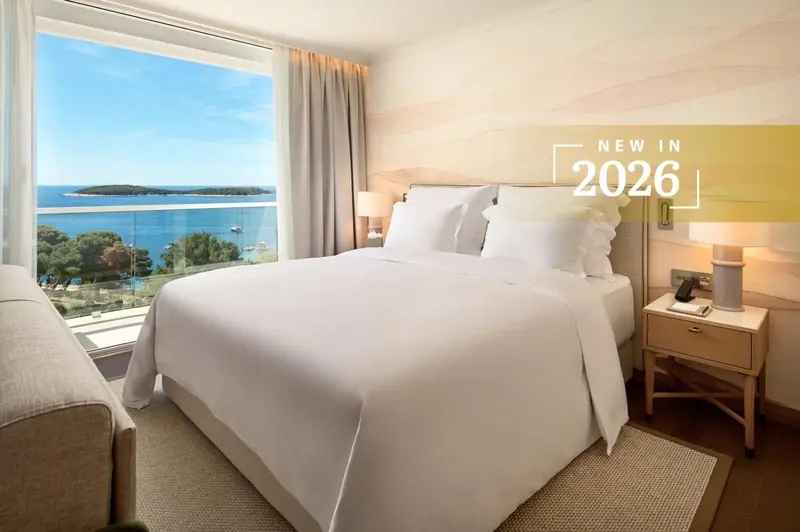 Chambre lumineuse avec un grand lit et vue sur la mer.