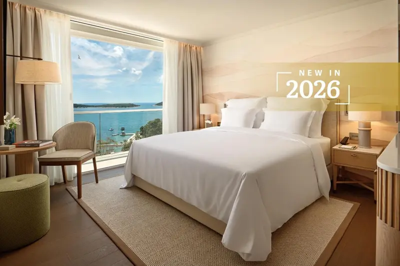 Chambre lumineuse avec un grand lit et vue sur la mer.