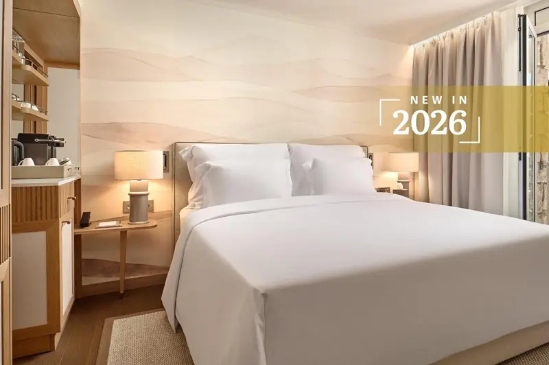 Une chambre lumineuse avec un grand lit recouvert de draps blancs.