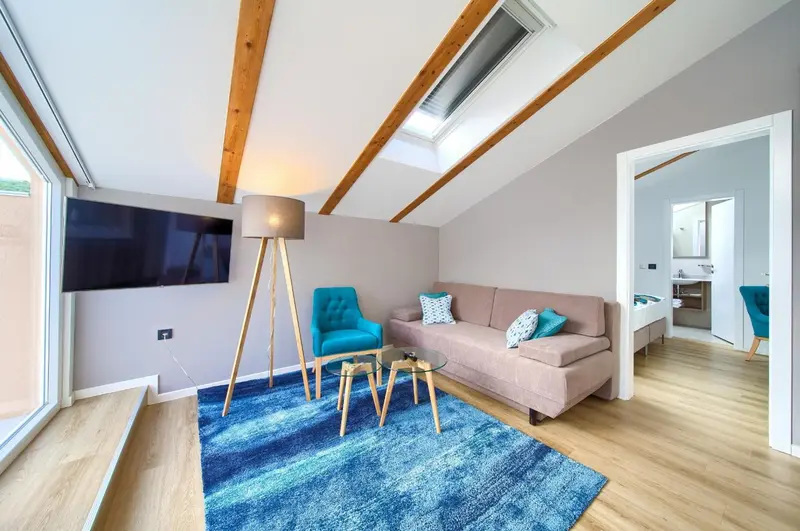 Une pièce de séjour lumineuse avec canapé, fauteuil et télévision.