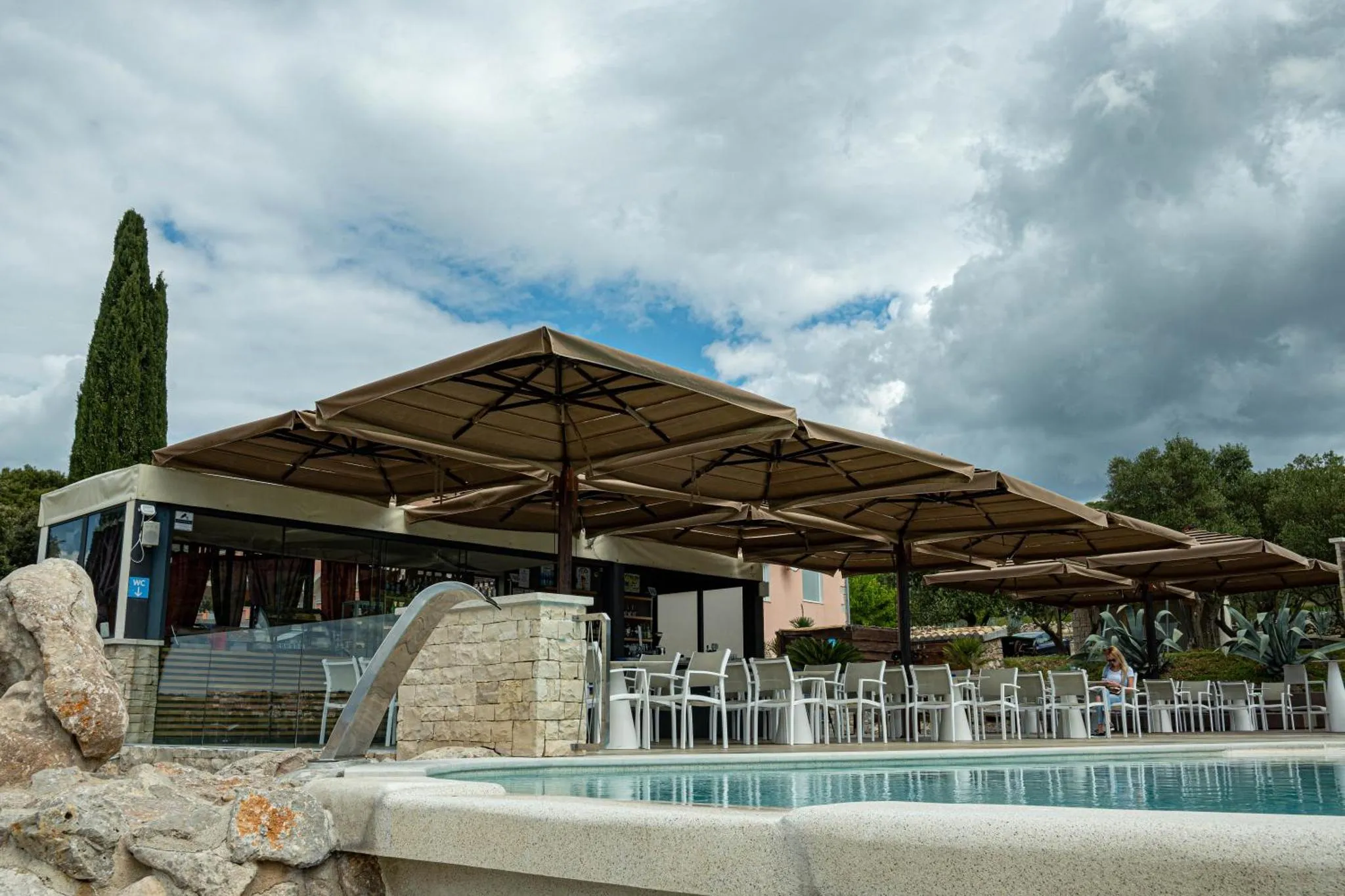 Terrasse ombragée avec mobilier blanc près d'une piscine.