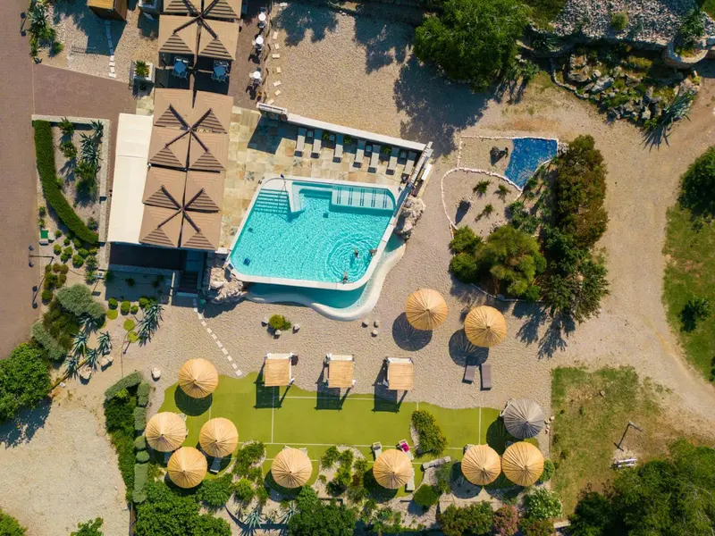 Vue aérienne d'une piscine et d'une terrasse avec parasols.