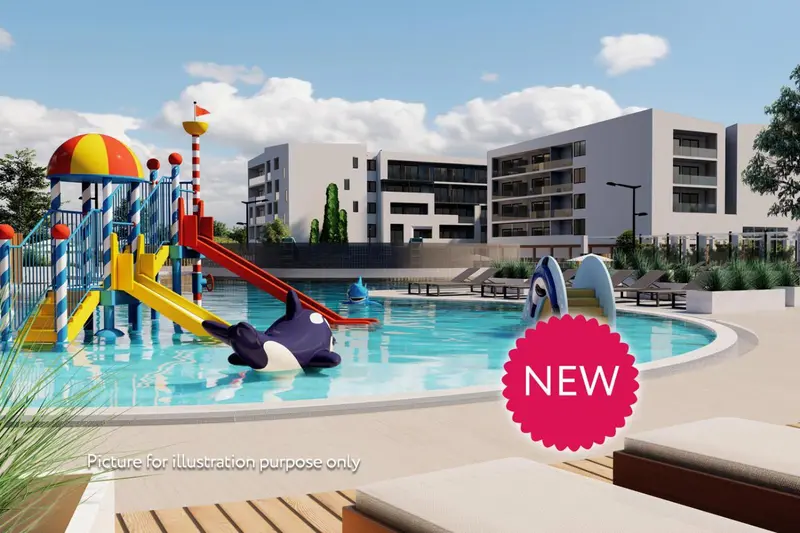 Une piscine pour enfants avec des jeux colorés et un bâtiment moderne en arrière-plan.