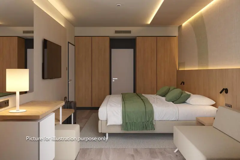 Chambre moderne avec un lit recouvert d'une couette verte et des oreillers.