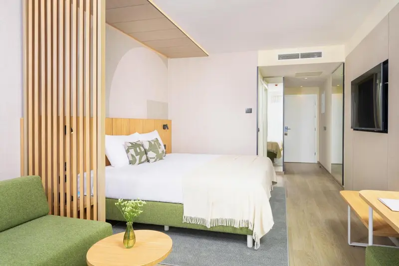 Une chambre lumineuse avec un lit double et un coin salon.