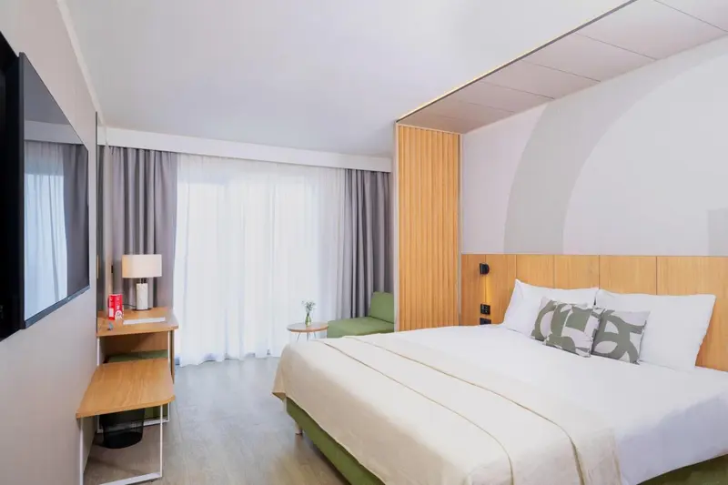 Une chambre lumineuse avec un grand lit et un coin salon.