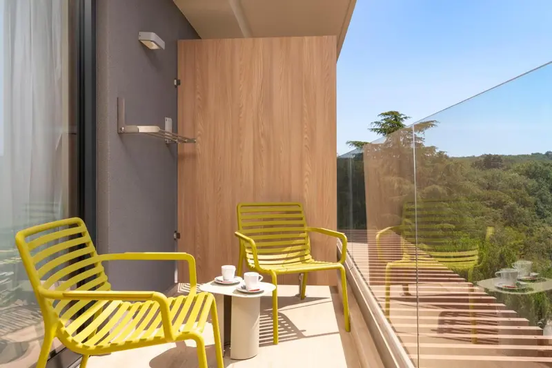 Deux fauteuils jaunes sur une terrasse avec vue sur la végétation.