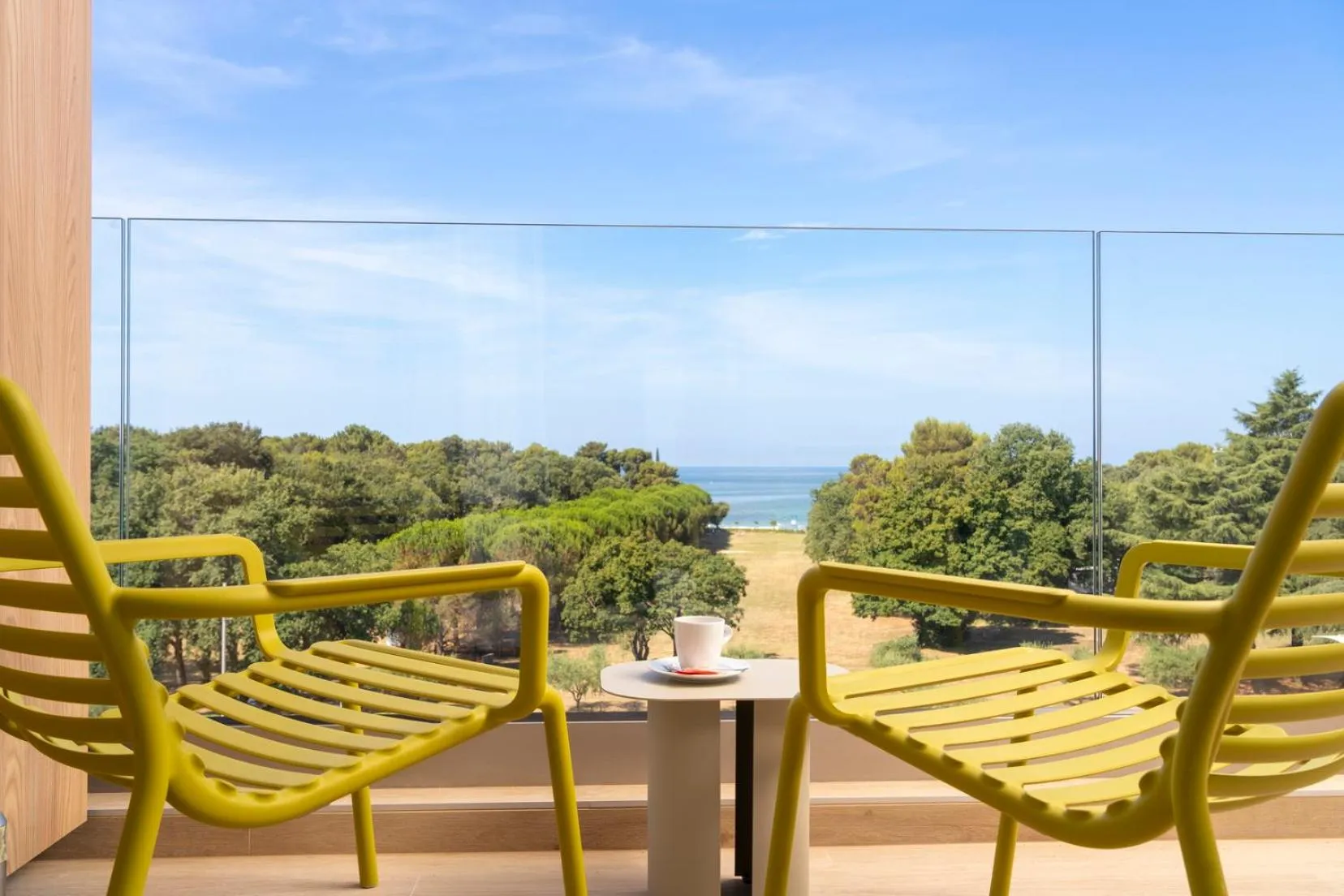 Deux fauteuils jaunes face à une vue sur la mer et la végétation.