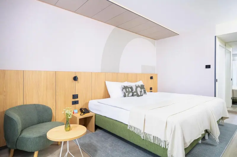 Une chambre lumineuse avec un grand lit et un fauteuil.
