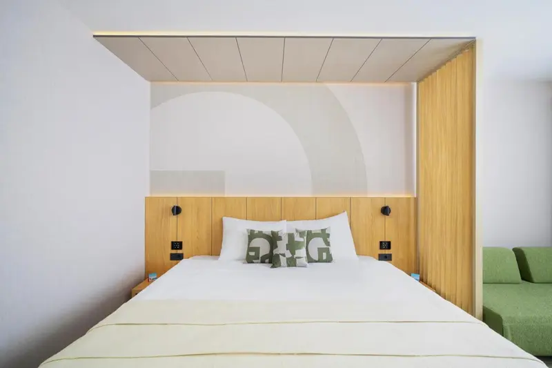 Un lit double avec des oreillers blancs et un chevet en bois.