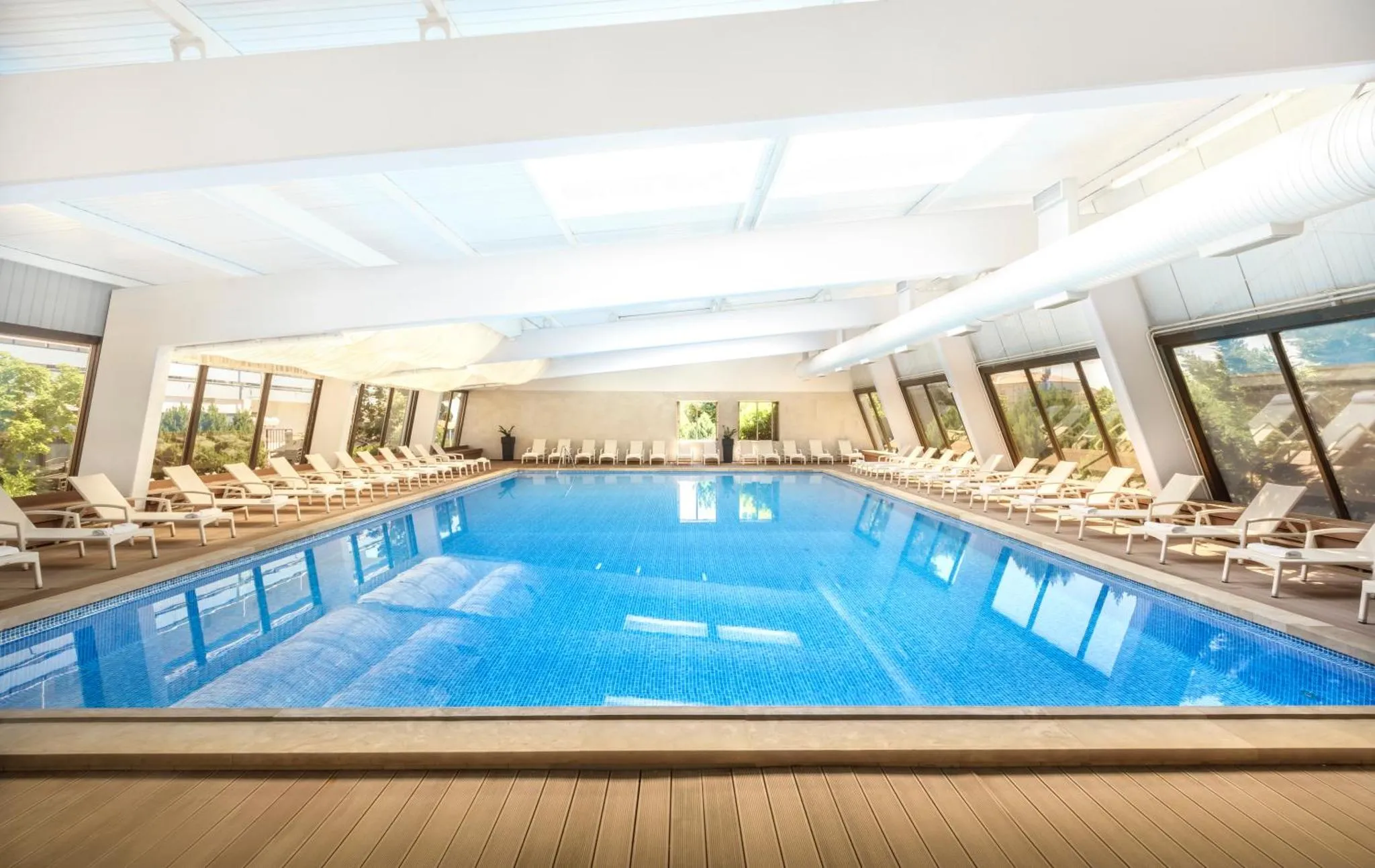 Une piscine interieure rectangulaire avec des transats alignes sur les bords.