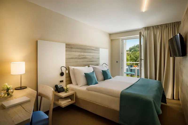 Une chambre lumineuse avec un grand lit et un accès à un balcon.