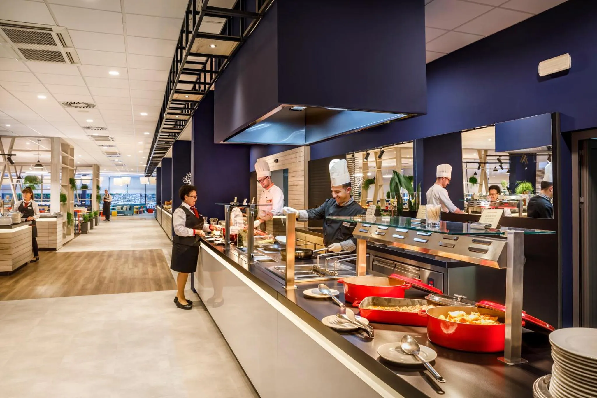 Un buffet propose une variété de plats chauds et froids servis par un personnel attentif.