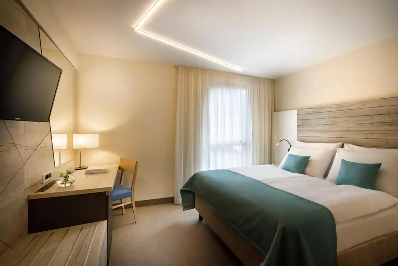 Une chambre lumineuse avec un lit double et un espace bureau.