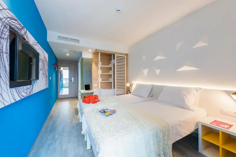Chambre lumineuse avec un grand lit recouvert d'une couverture blanche et d'oreillers.